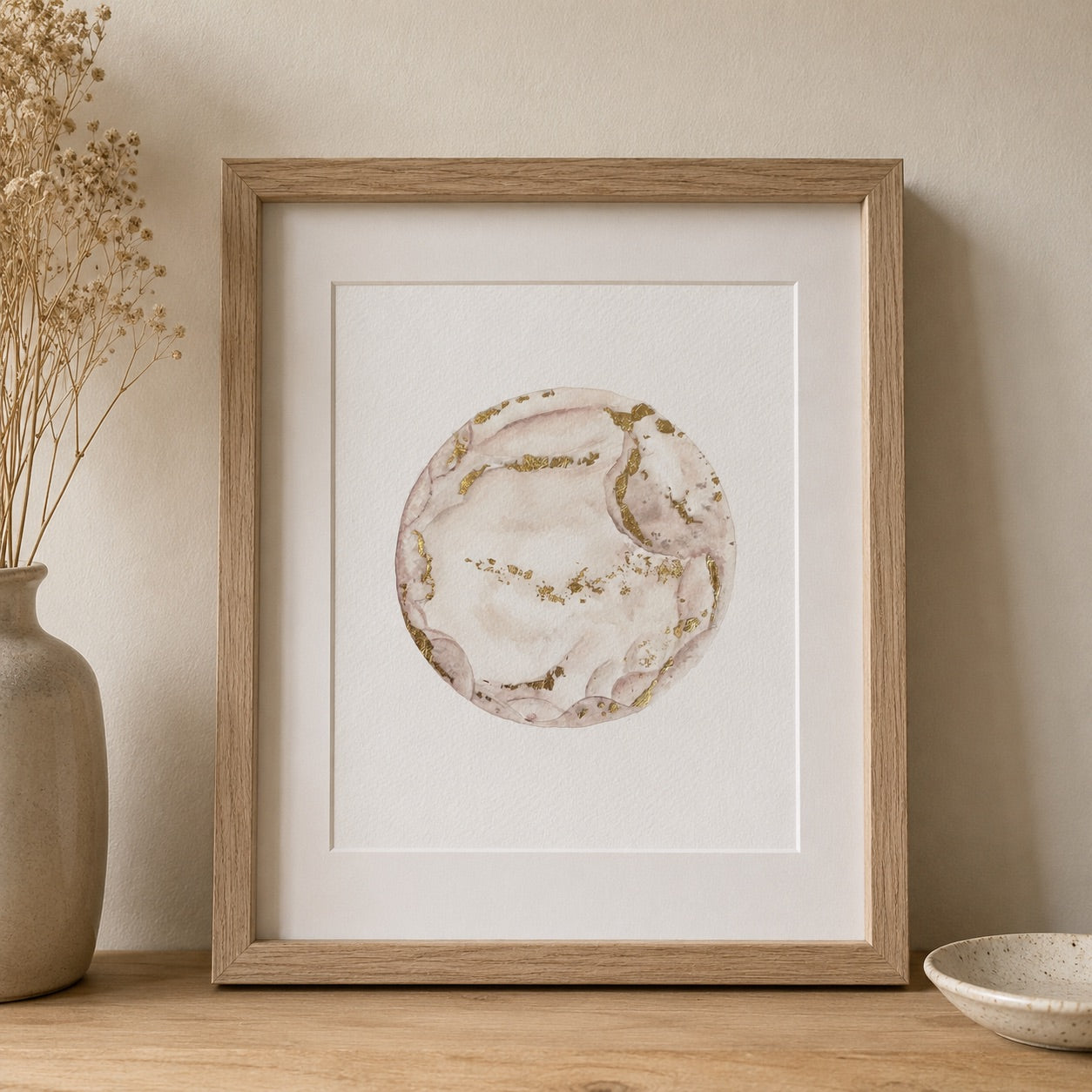 Framed watercolour embryo artwork on a wall with a vase and bowl in the foreground.