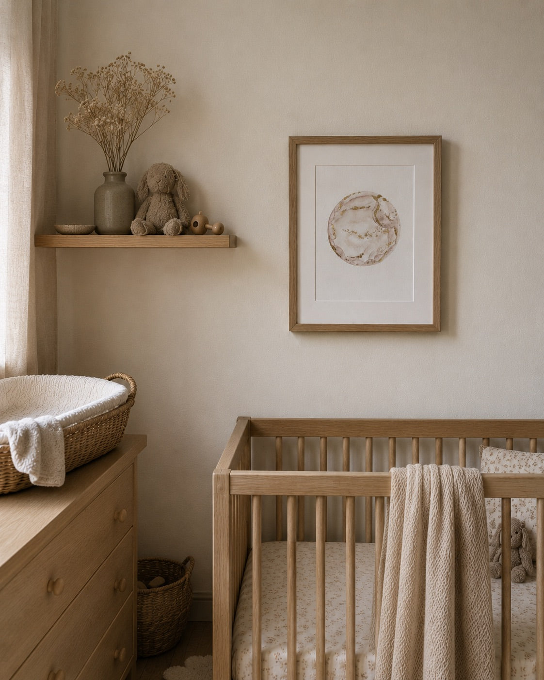 Nursery room with wooden crib, dresser, and framed watercolour embryo artwork on a beige wall.